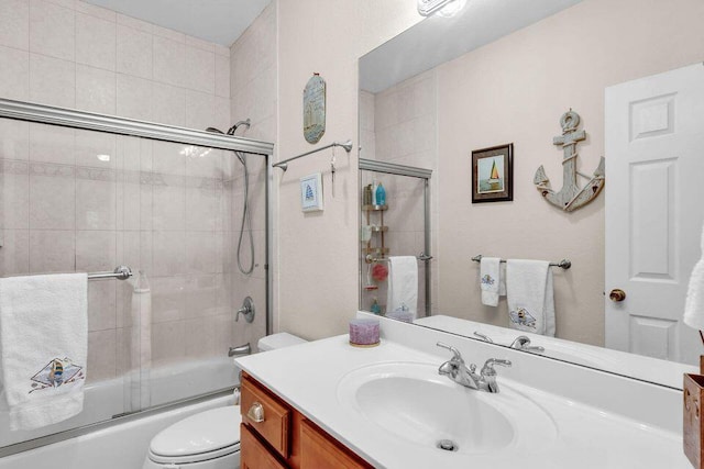 full bathroom with enclosed tub / shower combo, vanity, and toilet