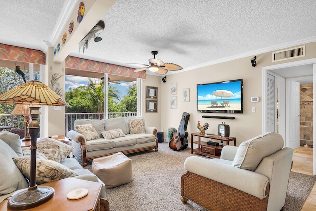 living room featuring ceiling fan, ornamental molding, plenty of natural light, and a textured ceiling