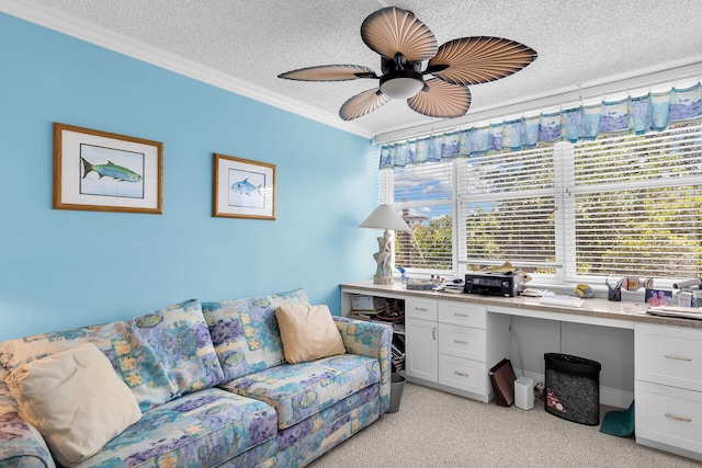 carpeted home office with ceiling fan, built in desk, ornamental molding, and a textured ceiling