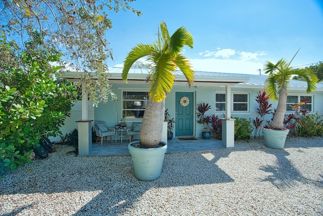 view of front of property featuring covered porch, metal roof, and stucco siding