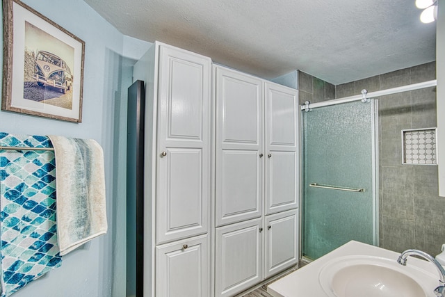 bathroom with vanity, a shower with door, and a textured ceiling