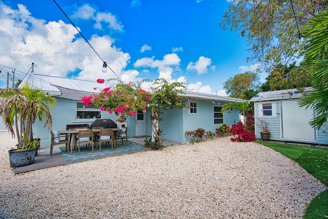 back of house featuring a storage shed, a patio, an outdoor structure, and stucco siding