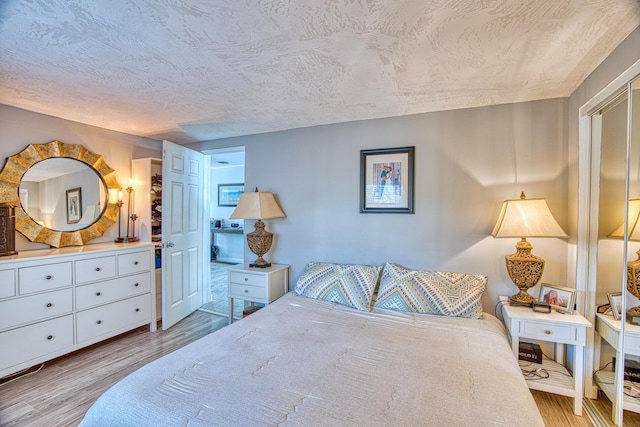 bedroom with light wood-style flooring and a textured ceiling