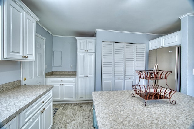 kitchen with crown molding, light hardwood / wood-style flooring, stainless steel refrigerator, and white cabinets