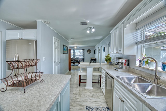 kitchen featuring a sink, stainless steel appliances, crown molding, and white cabinetry