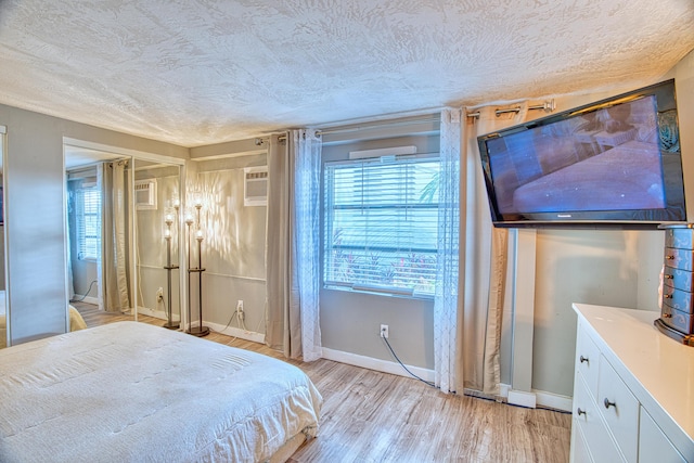 bedroom with light wood finished floors, a textured ceiling, and baseboards