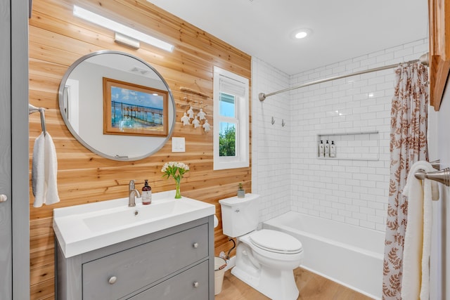 full bathroom featuring shower / tub combo, wooden walls, vanity, wood-type flooring, and toilet