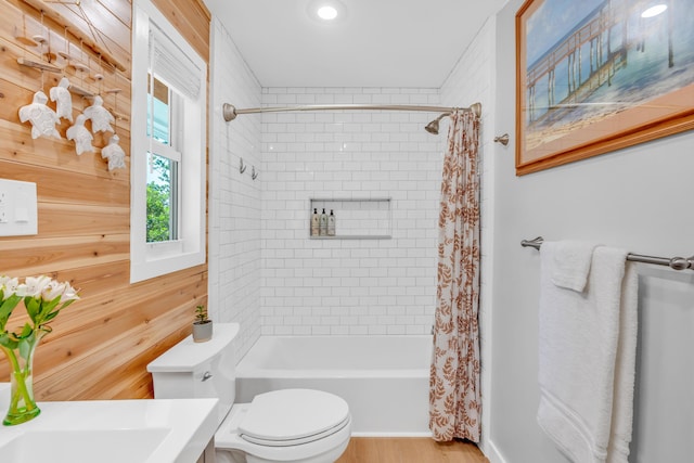 bathroom featuring wood-type flooring, shower / bathtub combination with curtain, and toilet