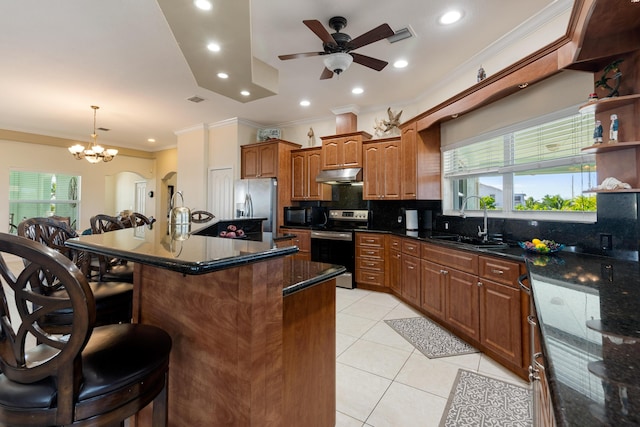 kitchen with light tile patterned floors, sink, backsplash, stainless steel appliances, and an island with sink