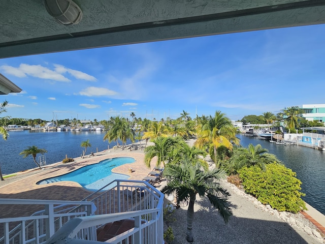 view of swimming pool featuring a patio and a water view