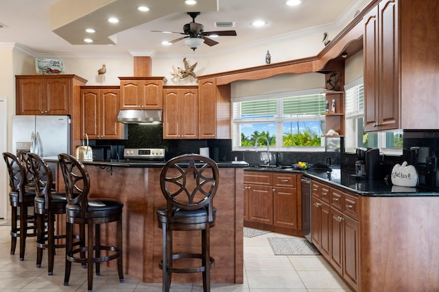 kitchen with tasteful backsplash, a kitchen bar, a center island, stainless steel appliances, and crown molding