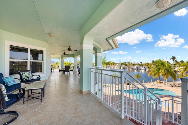 balcony featuring a water view, ceiling fan, and a patio