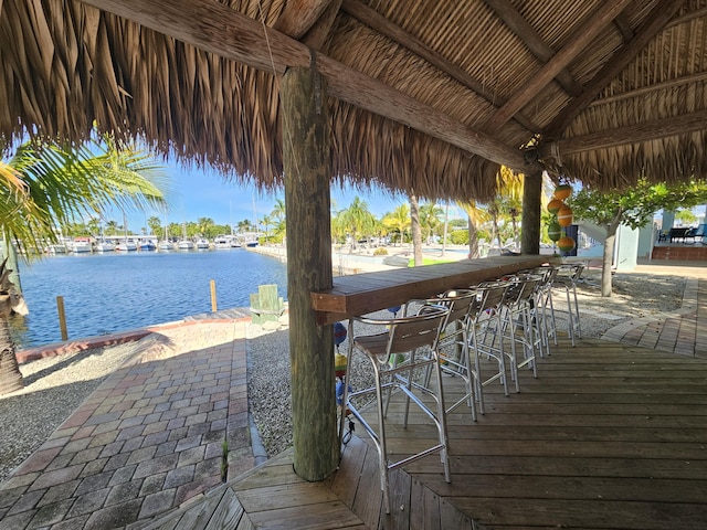 wooden terrace featuring a water view, exterior bar, and a gazebo