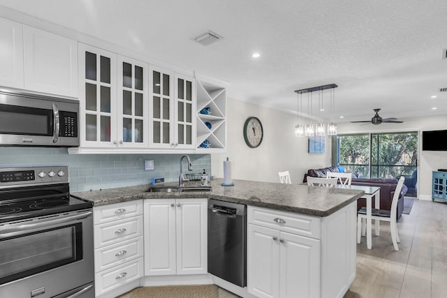 kitchen with sink, white cabinetry, decorative light fixtures, appliances with stainless steel finishes, and kitchen peninsula