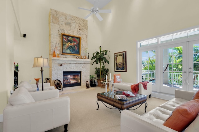 living area featuring a stone fireplace, a towering ceiling, and carpet floors