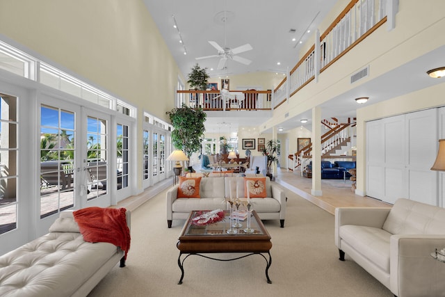 living area with a high ceiling, stairway, a ceiling fan, and visible vents