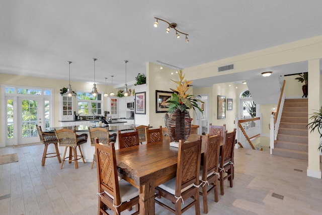 dining room featuring visible vents, plenty of natural light, stairs, and light wood-style floors