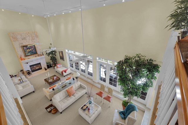 living room with a fireplace, rail lighting, and a towering ceiling