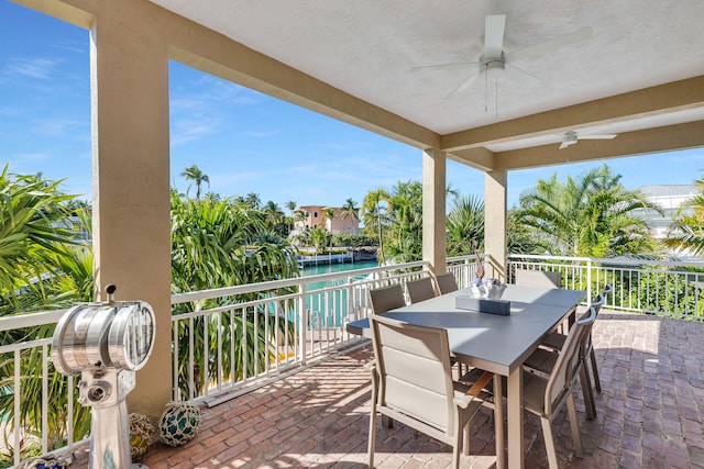 view of patio featuring outdoor dining area, a water view, and ceiling fan