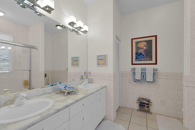 bathroom with tile patterned flooring, tile walls, tiled shower, and a sink