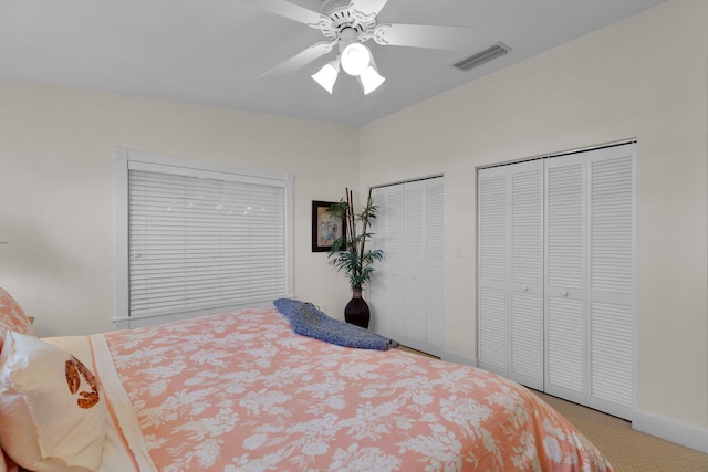 bedroom with visible vents, multiple closets, carpet, and a ceiling fan