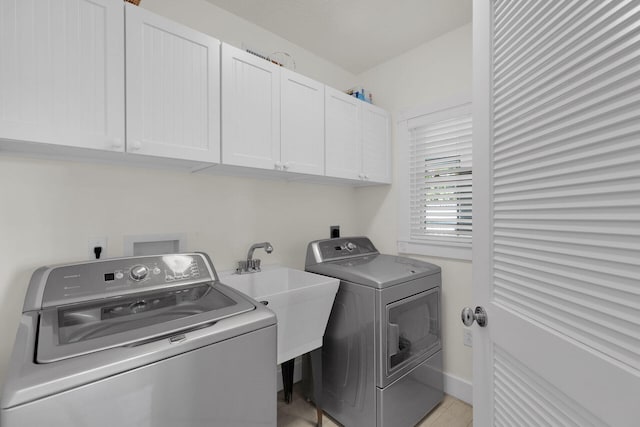 washroom featuring a sink, cabinet space, baseboards, and washing machine and clothes dryer