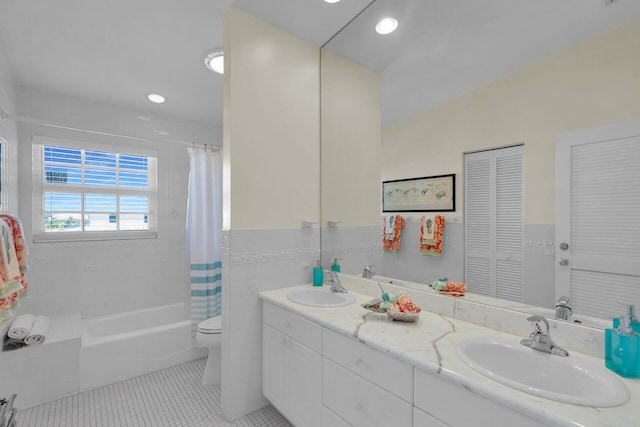 bathroom with tile walls, toilet, tile patterned floors, and a sink