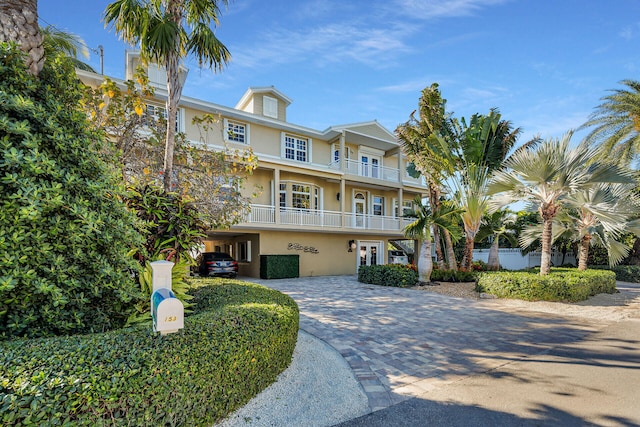 view of front facade with decorative driveway, a balcony, french doors, and stucco siding