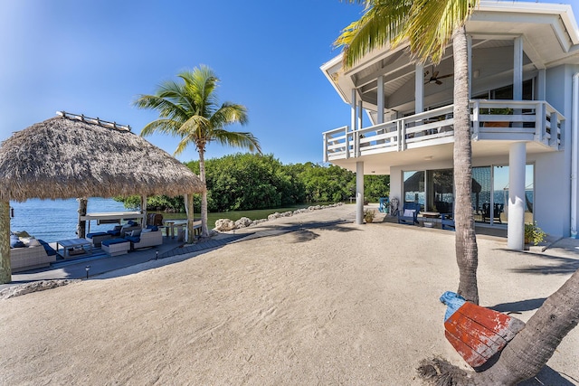 exterior space featuring a water view, a gazebo, a ceiling fan, a patio area, and a balcony