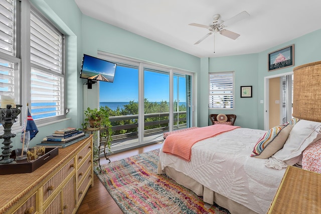 bedroom featuring access to outside, multiple windows, a ceiling fan, and wood finished floors