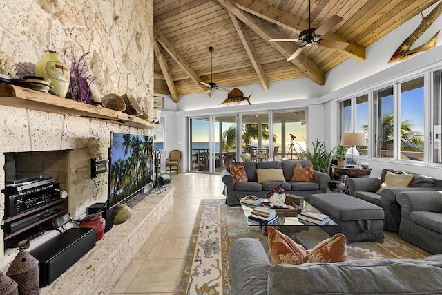 living room with beam ceiling, wood ceiling, light tile patterned flooring, a stone fireplace, and high vaulted ceiling