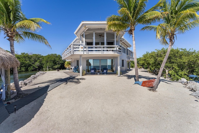 back of property with a ceiling fan, a patio area, and a water view