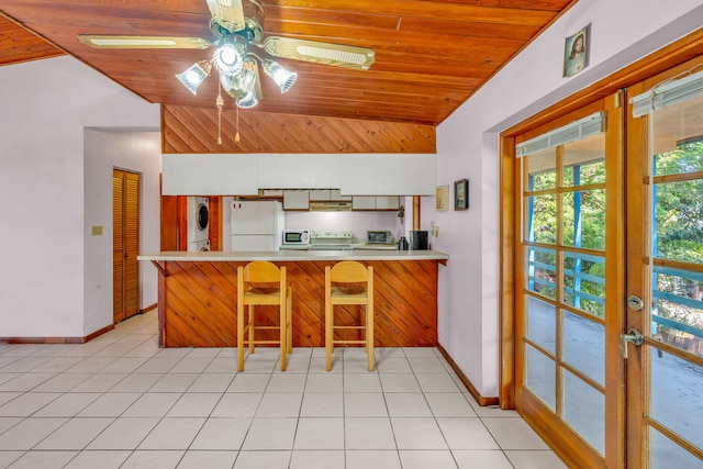 kitchen featuring vaulted ceiling, wooden ceiling, kitchen peninsula, white fridge, and stacked washing maching and dryer