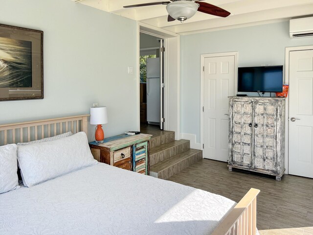 bedroom featuring wood-type flooring, white fridge, a wall mounted AC, and ceiling fan