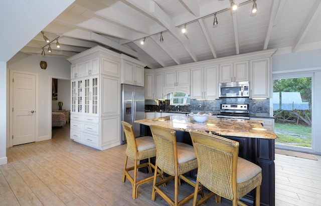 kitchen featuring a kitchen island, light stone countertops, appliances with stainless steel finishes, and decorative backsplash