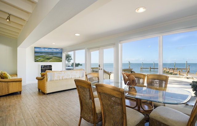 dining space with light hardwood / wood-style flooring, ornamental molding, and french doors