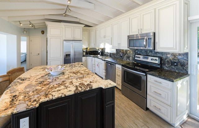 kitchen featuring dark stone countertops, stainless steel appliances, a center island, and white cabinets