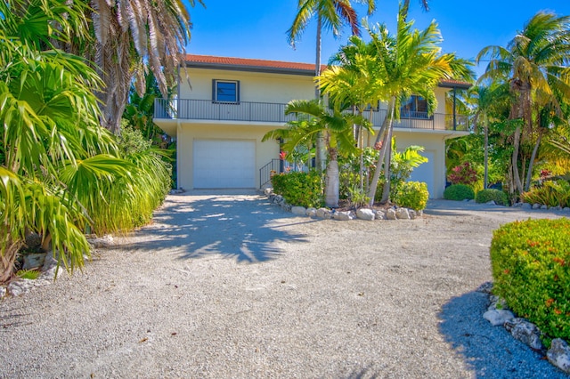 564 Sombrero Beach Rd, Marathon, FL 33050 - view of front of property featuring a balcony, dirt driveway, a garage, and stucco siding