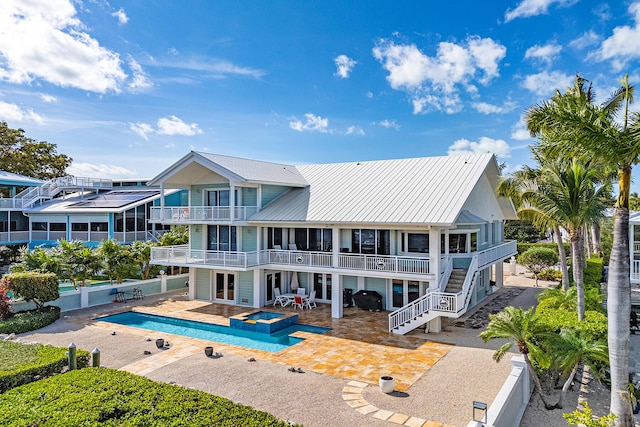 rear view of property featuring a pool with hot tub, a patio area, and a balcony