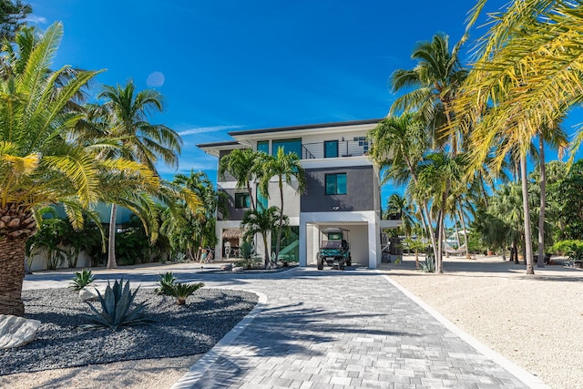 beach home featuring stucco siding, a carport, and decorative driveway