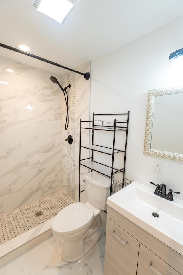 bathroom with vanity, toilet, and a tile shower