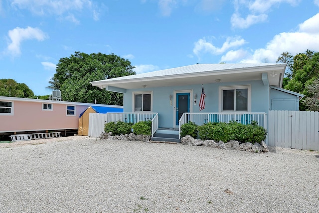 939 Plantation Rd, Key Largo, FL 33037 - view of front of house featuring a gate, a porch, stucco siding, and a metal roof