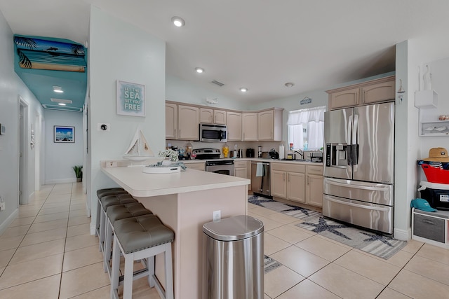 939 Plantation Rd, Key Largo, FL 33037 - kitchen featuring appliances with stainless steel finishes, a peninsula, light tile patterned floors, a kitchen breakfast bar, and lofted ceiling