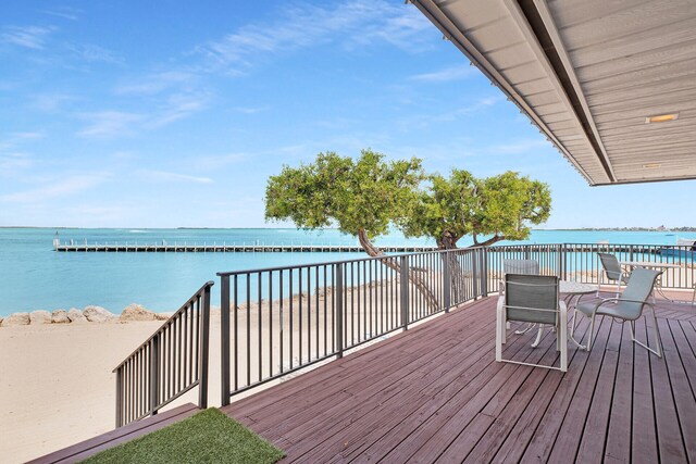 wooden deck with a water view and a beach view