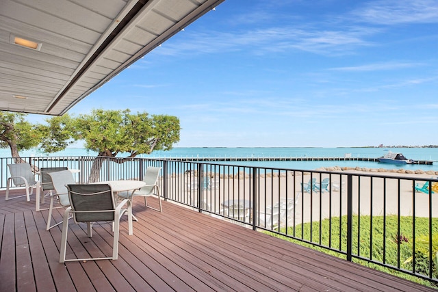 wooden deck featuring a water view and a beach view