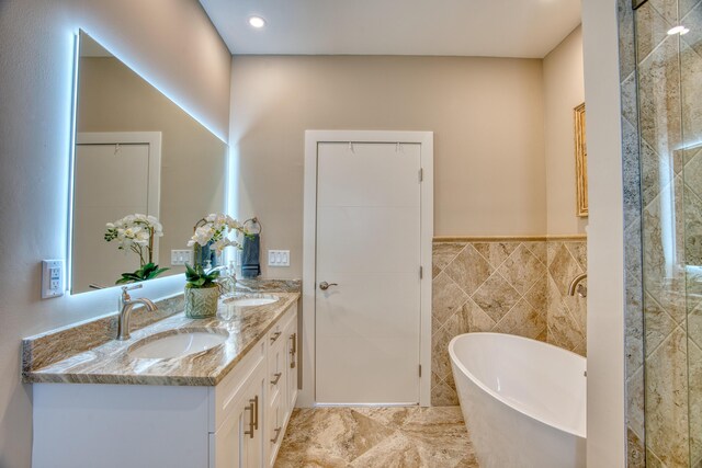 bathroom with vanity, a bath, and tile walls