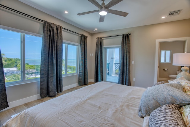 bedroom with multiple windows, ceiling fan, connected bathroom, and light hardwood / wood-style floors