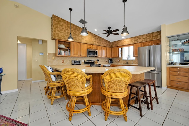 kitchen featuring light tile patterned flooring, a kitchen bar, sink, vaulted ceiling, and appliances with stainless steel finishes