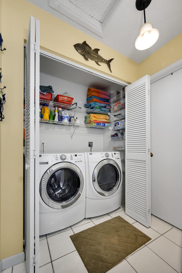 laundry room featuring a textured ceiling, washer and dryer, and light tile patterned floors