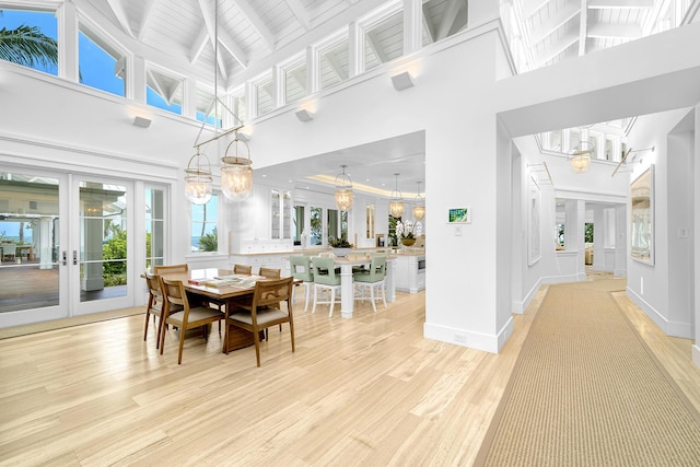 dining room with french doors, beam ceiling, light hardwood / wood-style floors, and a wealth of natural light